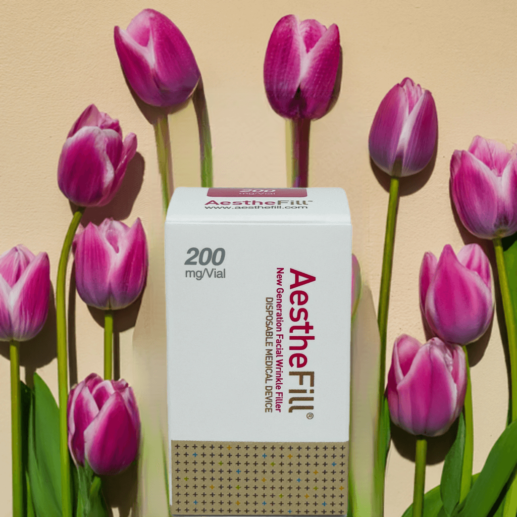 AestheFill 200mg vial from Nutrination surrounded by pink tulips on a soft background.